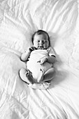 Newborn Baby in Onesie Sleeping on Bed, High Angle View
