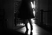 Waist-Down Silhouette of Young Woman in Skirt Walking Across Room With Light Coming Through Door