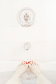Woman's Feet with Red Nail Polish Sticking out of Bath Tub