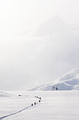 Group of skiers cross Portage Lake during a wind storm, Southcentral Alaska, Winter
