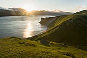 The sun setting behind Unimak Island from the bluff above the Laukitis fishcamp in False Pass, Southwest Alaska, summer.