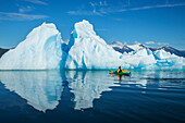 A sea kayaker paddles beside an iceberg in Southeast Alaska's Stephens Passage on a summer evening, Holkham Bay, Tracy Arm. MR_ Ed Emswiler, ID#:12172012A