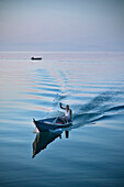 Fischer im Boot blickt in die Kamera und winkt, Murici, Skutari See National Park, Montenegro, Balkan Halbinsel, Europa