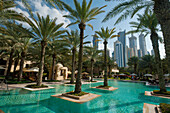 Swimming pool of the One and Only Royal Mirage with tower blocks behind, Dubai, UAE