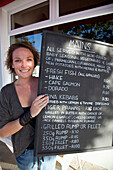 South Africa, Garden Route, Woman showing menu blackboard in Soul Mate Fish restaurant, Port Elizabeth