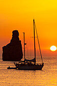 Yachts and strange shaped rock off Benirras Beach at dusk, Ibiza, Spain
