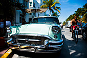 Cyclist passing 1950s classic Buick car, parked, Ocean Drive, South Beach, Miami, Florida, USA