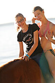 Two girls riding a horse at lake Starnberg, Ammerland, Munsing, Upper Bavaria, Germany