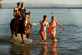 Vier Mädchen mit einem Pferd im Starnberger See, Ammerland, Münsing, Oberbayern, Bayern, Deutschland