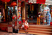 Mutter und Sohn sitzen auf einer Treppe vor einem Tempel, Chinatown, Singapur