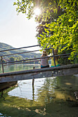 Two young women sitting on a jetty at river Rhine, Rheinfelden, Baden-Wuerttemberg, Germany