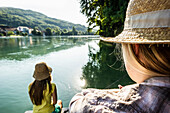 Zwei junge Frauen sitzen am Rheinufer, Rheinfelden, Baden-Württemberg, Deutschland