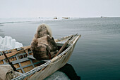 Bowhead Whale (Balaena mysticetus) hunter, an Inuit in traditional clothes sits in sealskin boat waiting for whales, Barrow, Alaska
