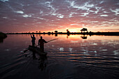 Fishermen in mokoro boat at sunrise, Chobe River, Namibia