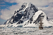 Rigged tourist ship Europa in heavy pack ice beneath Mount Scott, Penola Strait, Antarctic Peninsula, Antarctica