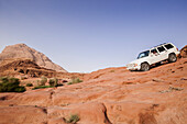 Off-road vehicle downhill driving above a slab of rock, Wadi Rum, Jordan, Middle East