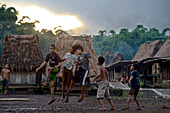 Children playing football on a muddy pitch in a traditional Ngada village, Bajawa, Flores, Nusa Tenggara Timur, Lesser Sunda Islands, Indonesia, Asia
