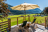 Liegestühle und Sonnenschirm auf einer Terrasse, Achensee und Achenkirch im Hintergrund, Tirol, Österreich