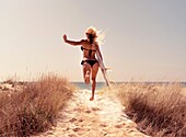 Woman with a surf board running to the beach. Tarifa, Costa de la Luz, Cadiz, Andalusia, Spain, Europe.
