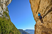 Frau steigt auf Klettersteig Sentiero Sega durch Felswand, Sentiero Sega, Monte Baldo, Gardaseeberge, Trentino, Italien