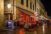 Menschen sitzen draußen vor einem Restaurant an der Stradun Hauptgasse der Altstadt am Abend, Dubrovnik, Dalmatien, Kroatien, Europa