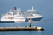 Fisherman on the pier with cruise ships MS Deutschland, Reederei Peter Deilmann, and Queen Elizabeth, Cunard in teh background, Kerkyra, Corfu Town, Corfu, Ionian Islands, Greece