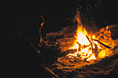 Junge Frau sitzt an einem Lagerfeuer, Grasgehren, Obermaiselstein, Bayern, Deutschland