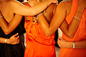 Backs of women standing together with their arms wrapped around each other