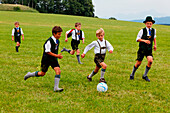 Kids in traditional bavarian dress playing football, Jasberg, Dietramszell, Upper Bavaria, Bavaria, Germany