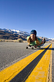 Young woman skateboarding in Bishop, CA with mountains in the background Bishop, California, USA
