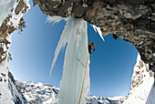A professional male climber ascends a frozen waterfall pillar while ice climbing near Ouray, Colorado Ouray, Colorado, USA