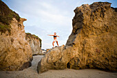 A young woman performing yoga on the beach Malibu, California, USA