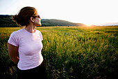 A girl in sunglasses walks in the tall grass watching the sunset Jackson, Wyoming, USA