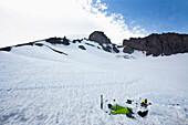 A climber melts snow near his campsite where two bivy sacks are set up Mount Rainier, Washington, USA