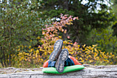 Teenager with feet up on a log taking a nap in woods deep in Glacier National Park Glacier National Park, Montana, USA