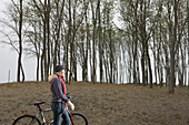 Single woman walking bike through a grey urban park Seattle, Washington, USA