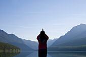 Silhouette of a woman practicing outdoor yoga at a remote lake in Glacier National Park Glacier National Park, Montana, USA