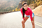 An athletic female stretches along a historic highway on a fall day Hood River, Oregon, USA