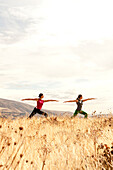 Two females practicing yoga in the outdoors in a field of dried grass Hood River, Oregon, USA