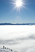 A man stops while skiing and looks out into a cloud-filled valley in Jackson Hole, Wyoming Jackson, Wyoming, USA