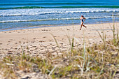 A woman runs along the soft sand at Sunshine Beach, Queensland, Australia Sunshine Coast, Queensland, Australia