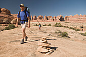 Man and woman hiking along a sandstone trail marked with cairns, Canyonlands National Park, Utah Monticello, Utah, USA