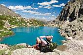 A woman hiker rests next to turquoise lake, Weminuche Wilderness, Colorado Durango, Colorado, USA