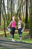 Two women in their mid-20's stretching leg muscles outdoors Dawsonville, Georgia, USA