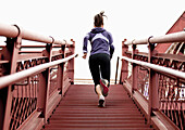 An athletic female in a purple jacket running stairs in Portland, Oregon Portland, Oregon, USA