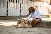 A woman in a cowboy hat pets a dog on the street in Brazil Brazil