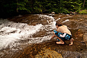 Testing the waters before jumping into the cold mountain stream Franconia, New Hampshire, USA