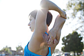 Woman stretches her arms before starting her exercise at the park in Coronado, California on a sunny day Coronado, California, USA