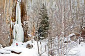 A man is standing at the base of a frozen waterfall in Sounkyo Gorge, Daisetsuzan National Park, Hokkaido, Japan Hokkaido, Japan