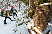 Two people are hiking on a trail next to a pillar with Japanese characters on it in Mount Fuji National Park, Honshu, Japan Honshu, Japan